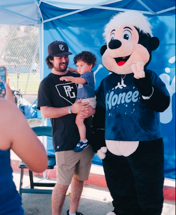 Drip posing with a dad and toddler at a Honee pop up