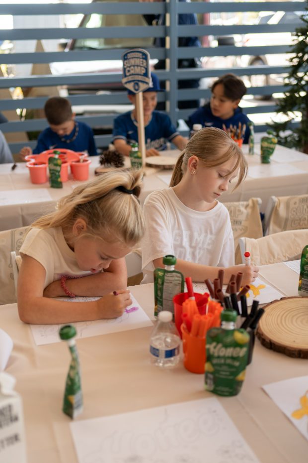 Kids coloring at the Sip & Learn craft table with Honee pouches