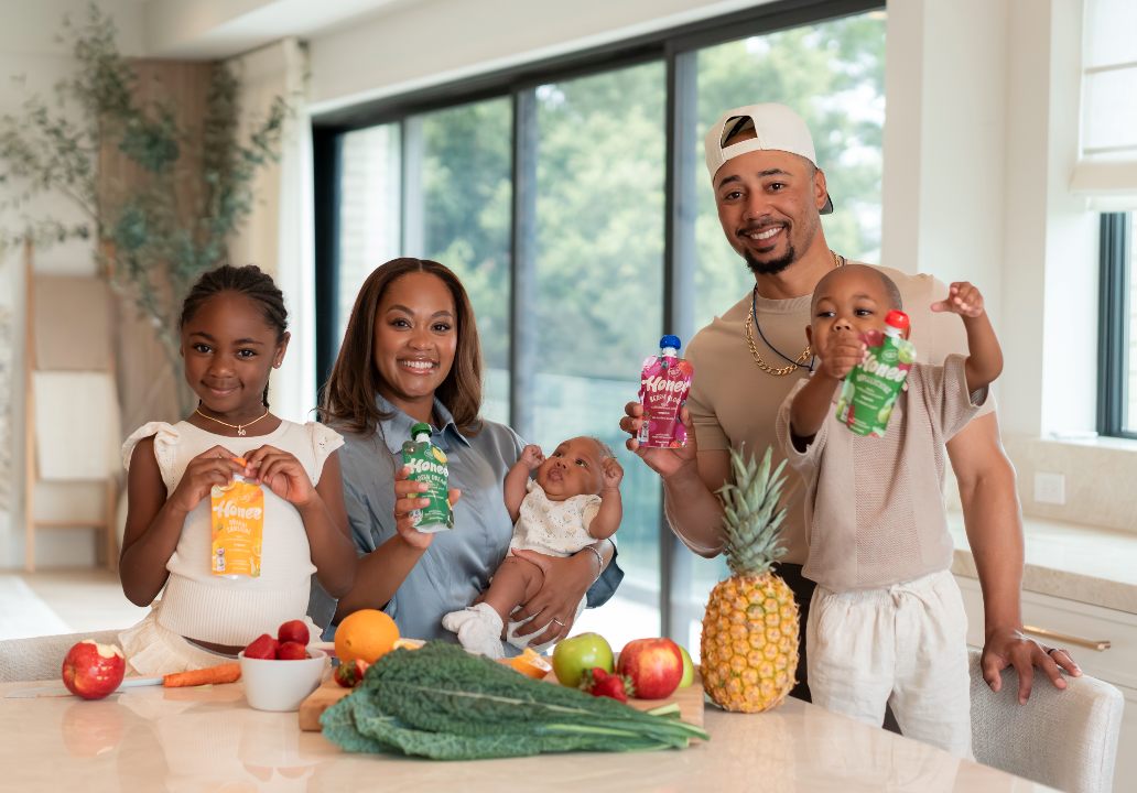 The Betts family in their kitchen holding Honee pouches with fresh fruit and vegetables