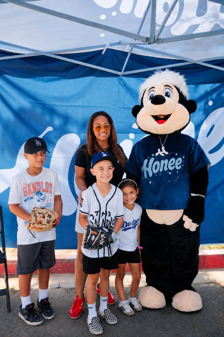 Kids posing with Drip the mascot under the Honee tent