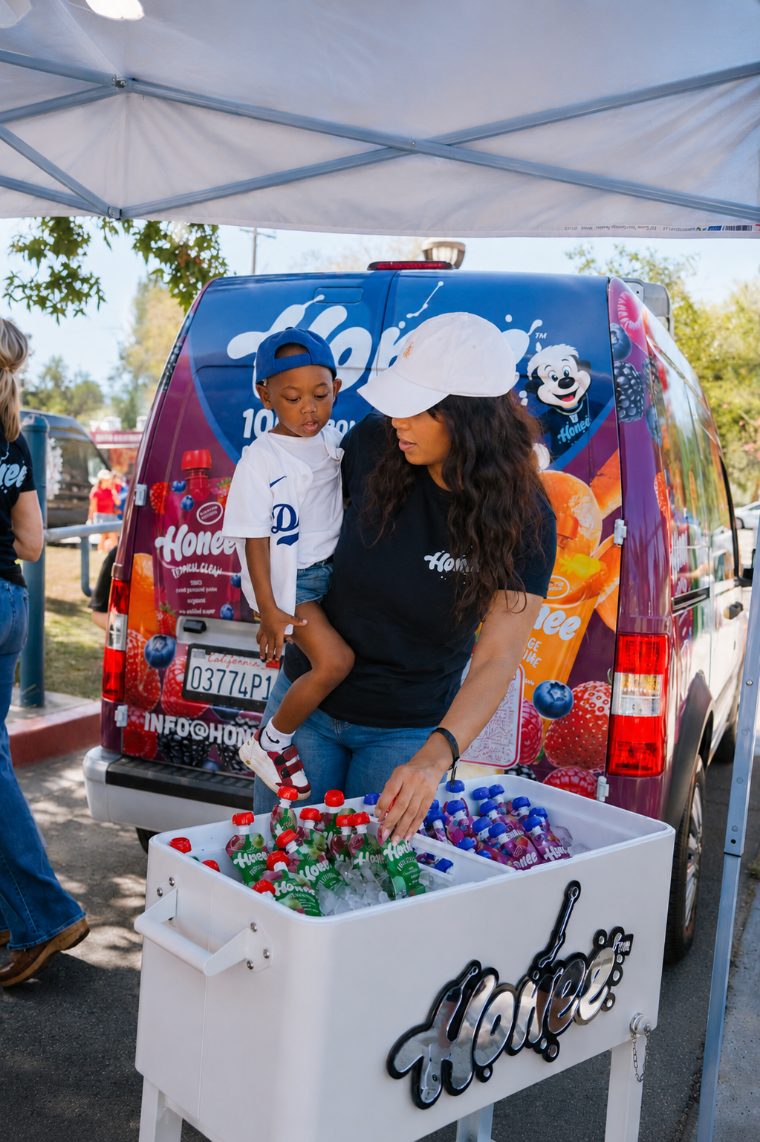 A team member and toddler at the cooler beside the Honee van