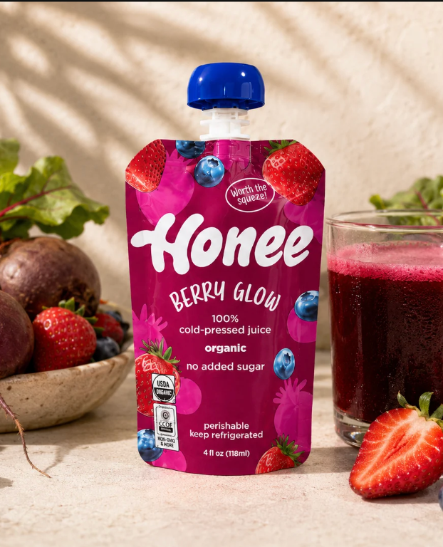 Honee Berry Glow pouch with fresh fruit and a glass of juice